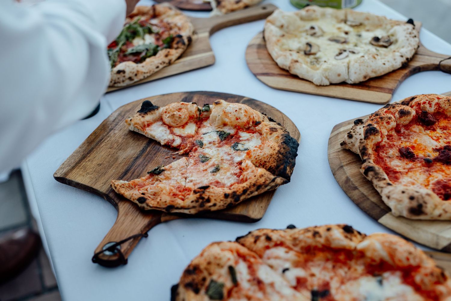 Rustic wood boards displaying artisanal pizzas with various toppings in a restaurant setting.