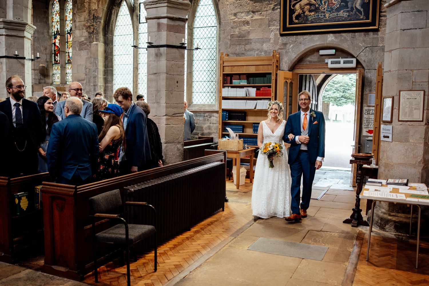 Wedding ceremony taking place inside a historic stone church with arched windows.