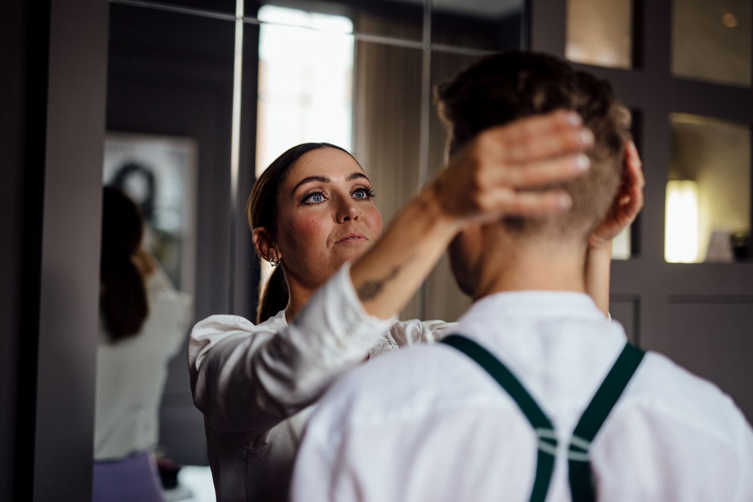 Person in white adjusts clothing in mirror reflection.