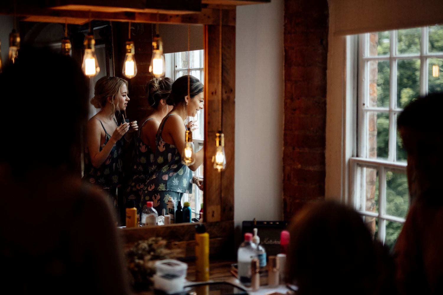 Warm lighting illuminates a rustic dining room with exposed brick walls and hanging pendant lights.