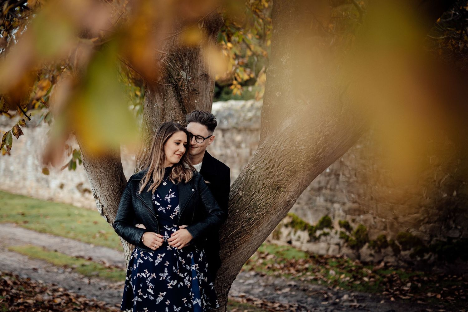 Autumn leaves frame intimate moment between couple in outdoor setting.