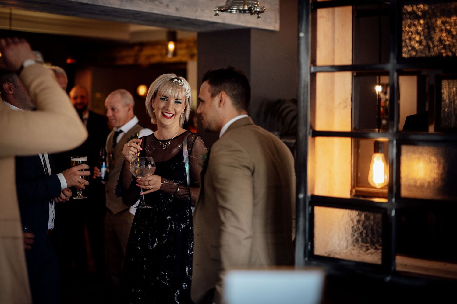 Evening reception gathering in a warmly lit venue with guests mingling.