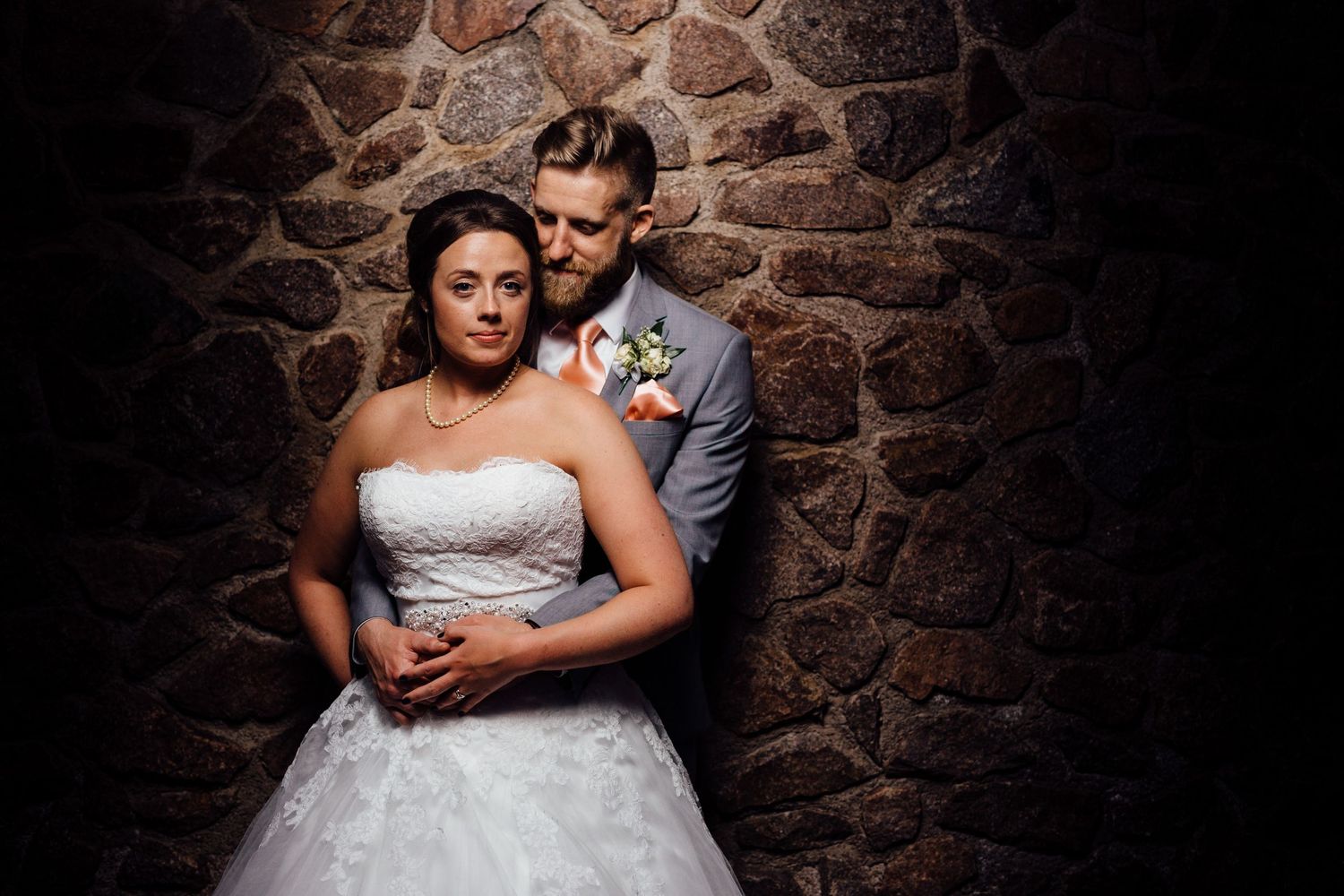 Romantic wedding portraits against a rustic stone wall background.