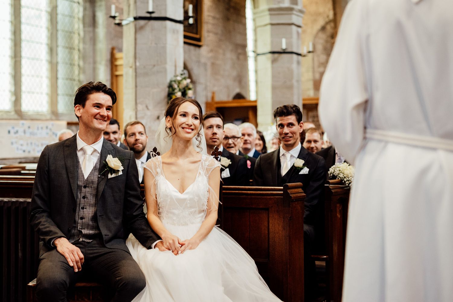 Wedding ceremony in progress inside a traditional stone church with ornate architectural details.
