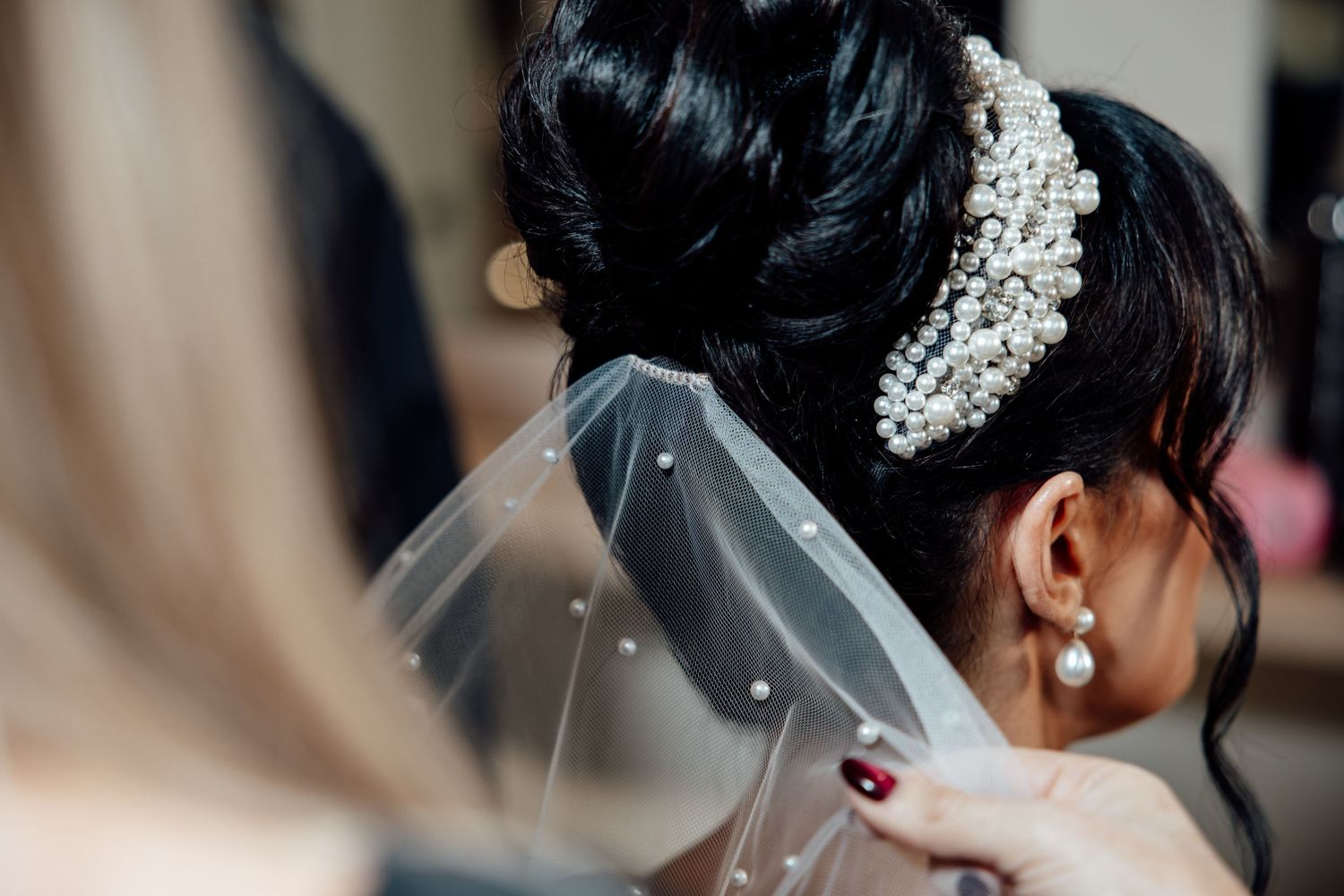 Close-up detail of an elegant bridal hairstyle with pearl hair accessories and veil.