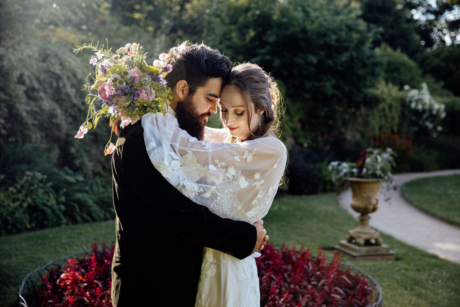 Intimate wedding portraits taken in a garden setting with vibrant red roses and natural light.