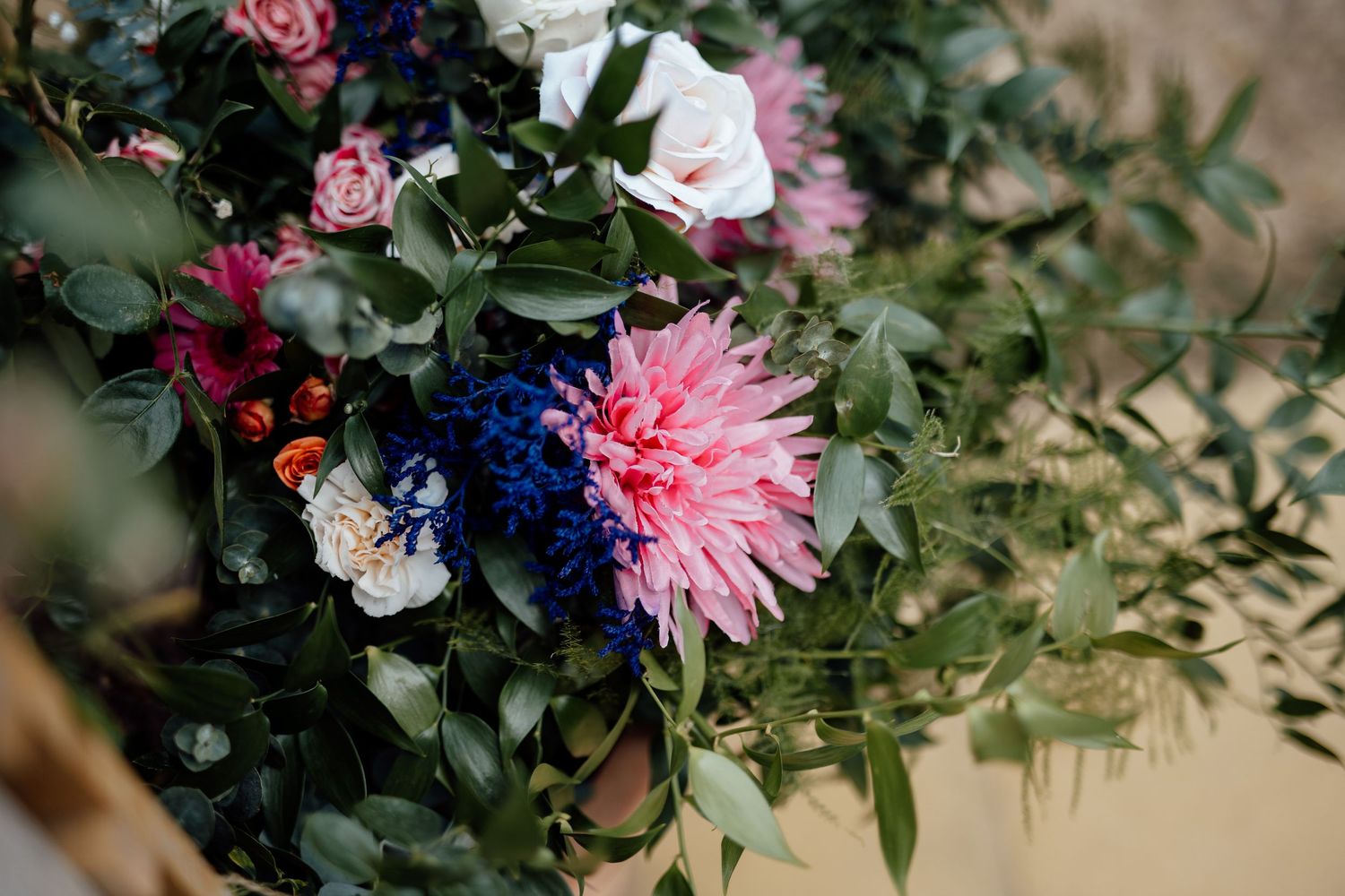 Close-up of a vibrant wedding bouquet featuring a pink dahlia, blue hydrangea, and lush greenery.