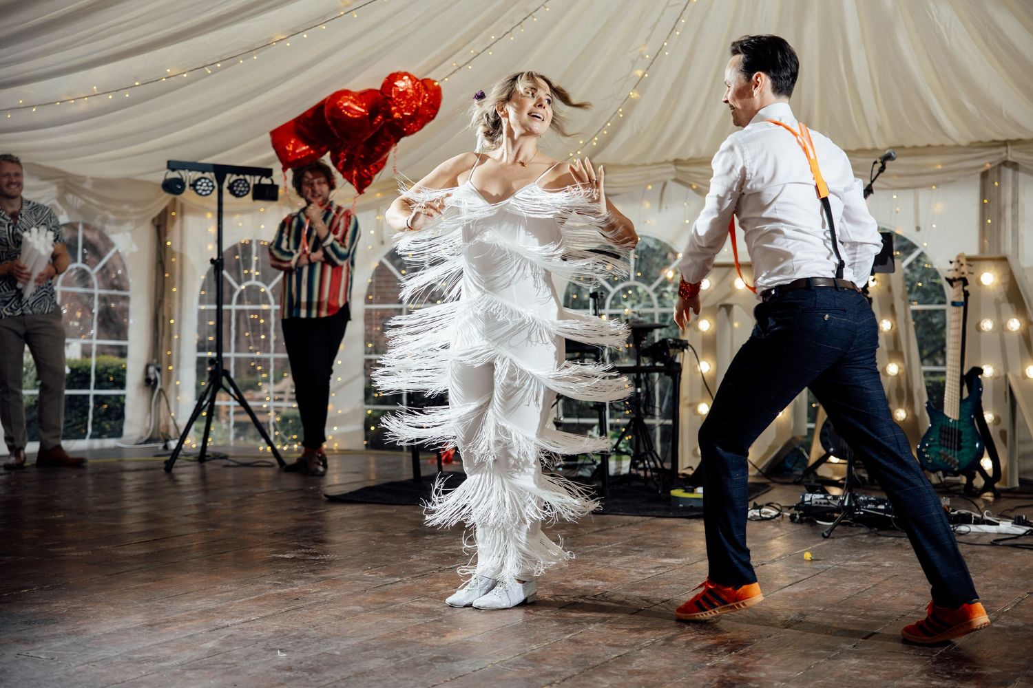 Dynamic dance floor moments captured during a wedding reception under a white tent.