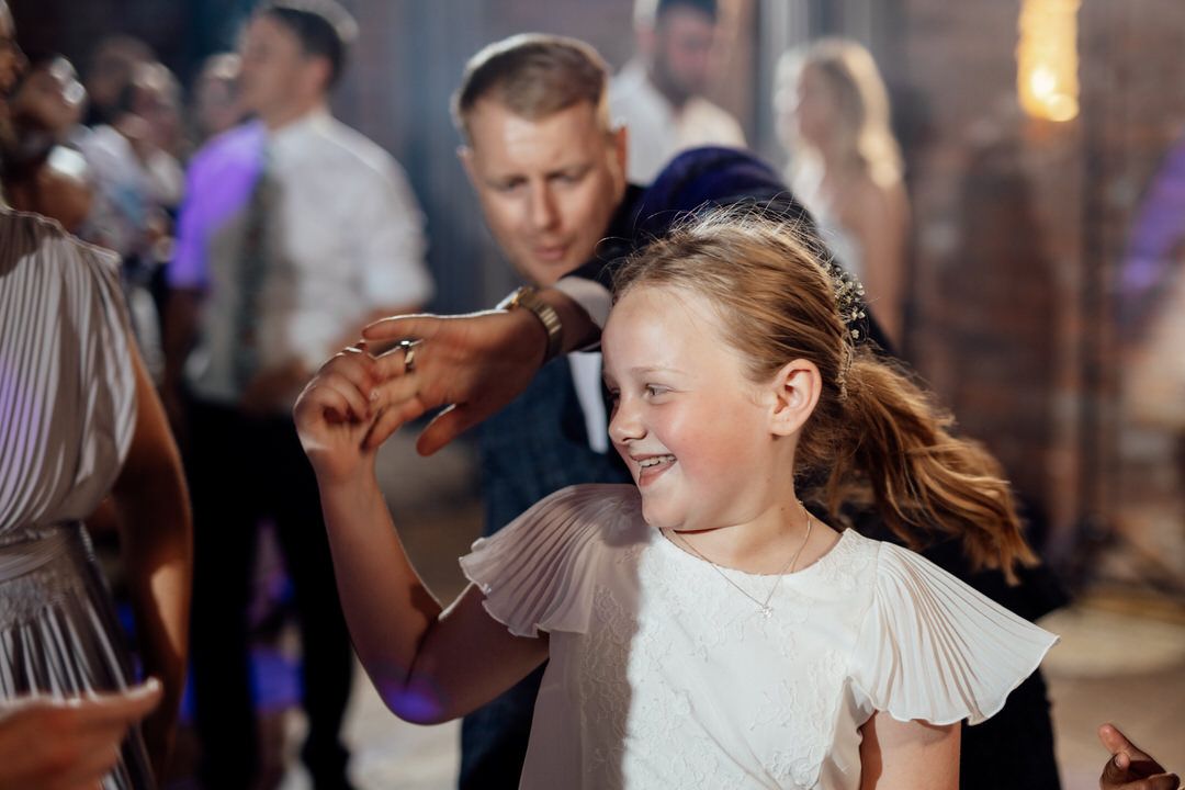 Wedding guests enjoying themselves on a lively dance floor with decorative lighting.
