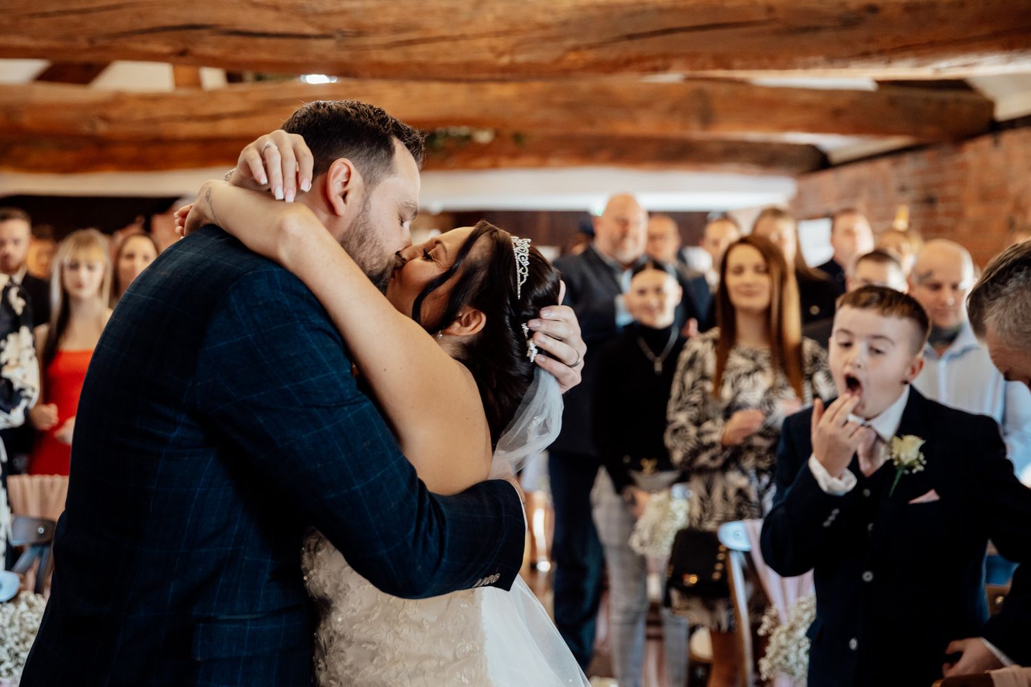 A couple shares their first dance surrounded by wedding guests in a rustic wooden venue.