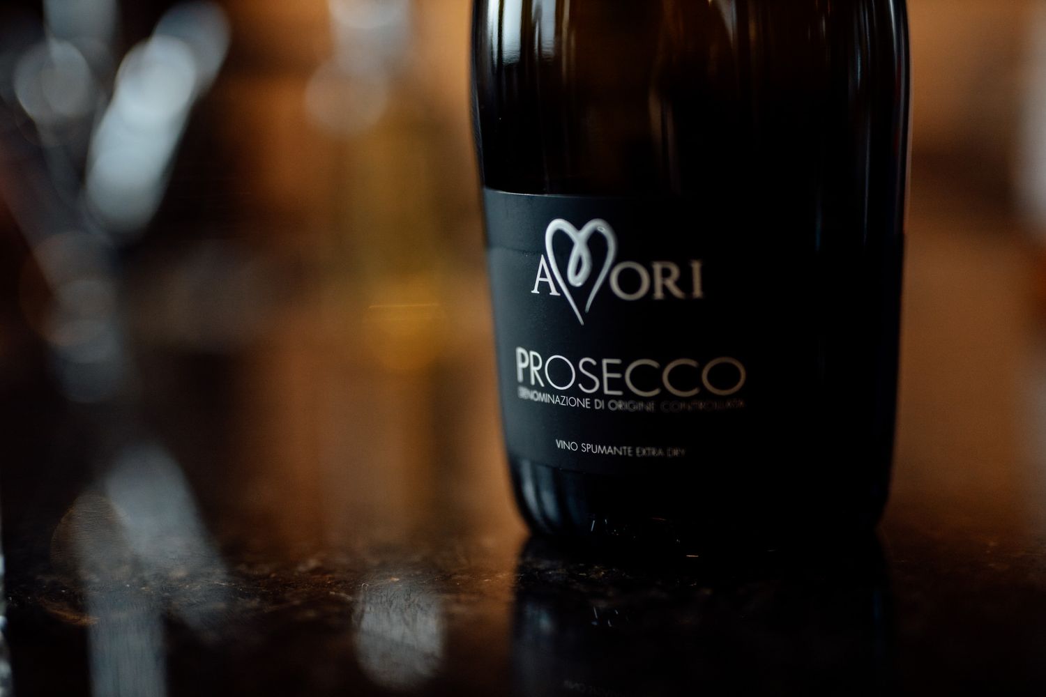 Close-up of prosecco bottles with blurred background at wedding reception.