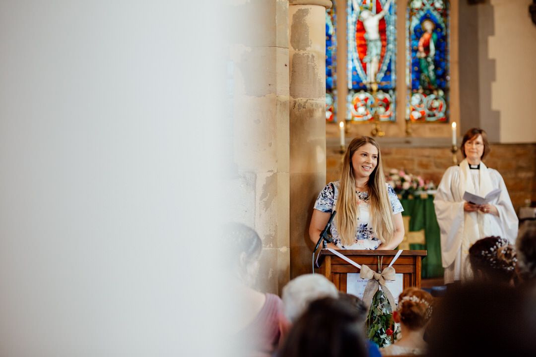 Wedding ceremony in progress inside traditional church with stained glass.
