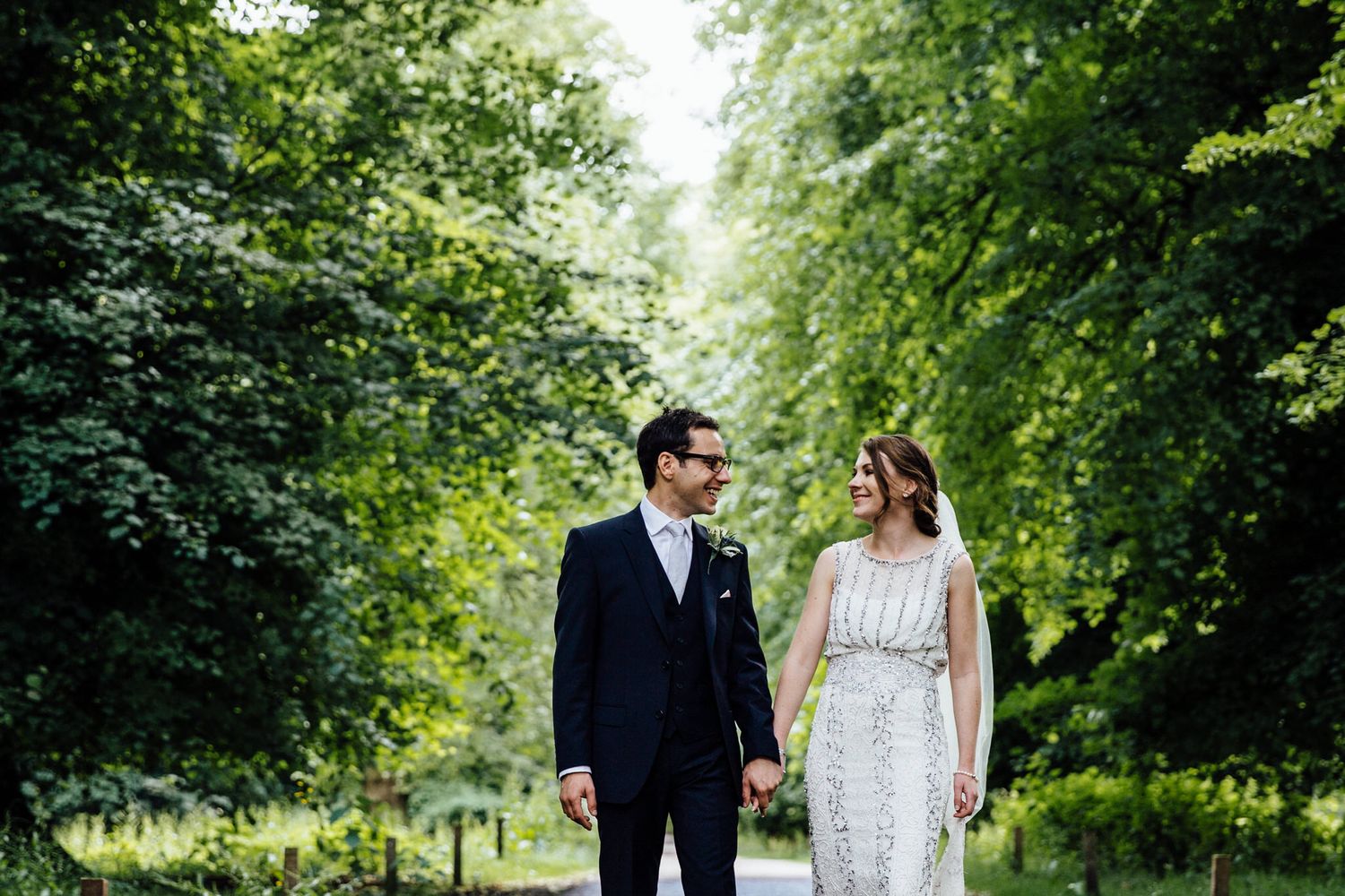 A romantic stroll through a wooded path with sunlight filtering through green summer foliage.