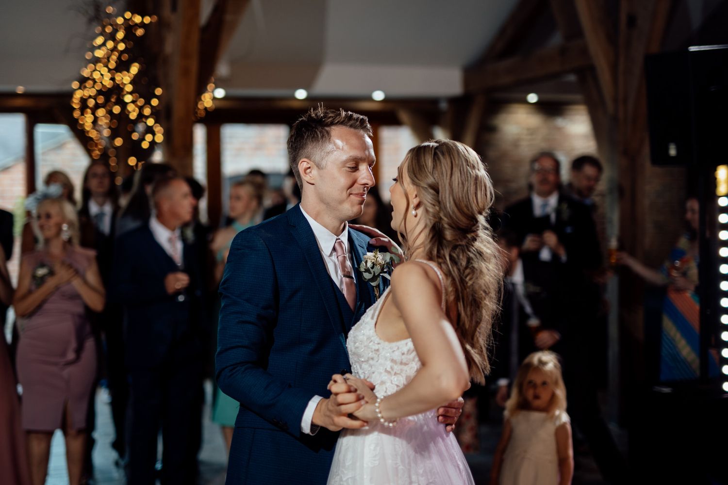 Couples dancing together at an elegant wedding reception with string lights overhead.