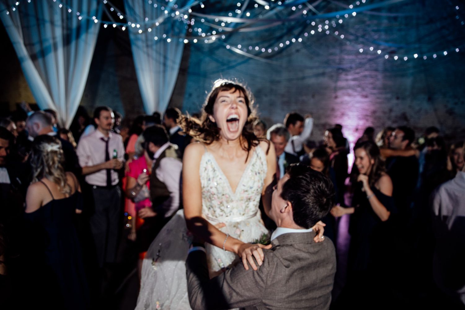 Wedding reception dance party with string lights creating magical atmosphere.