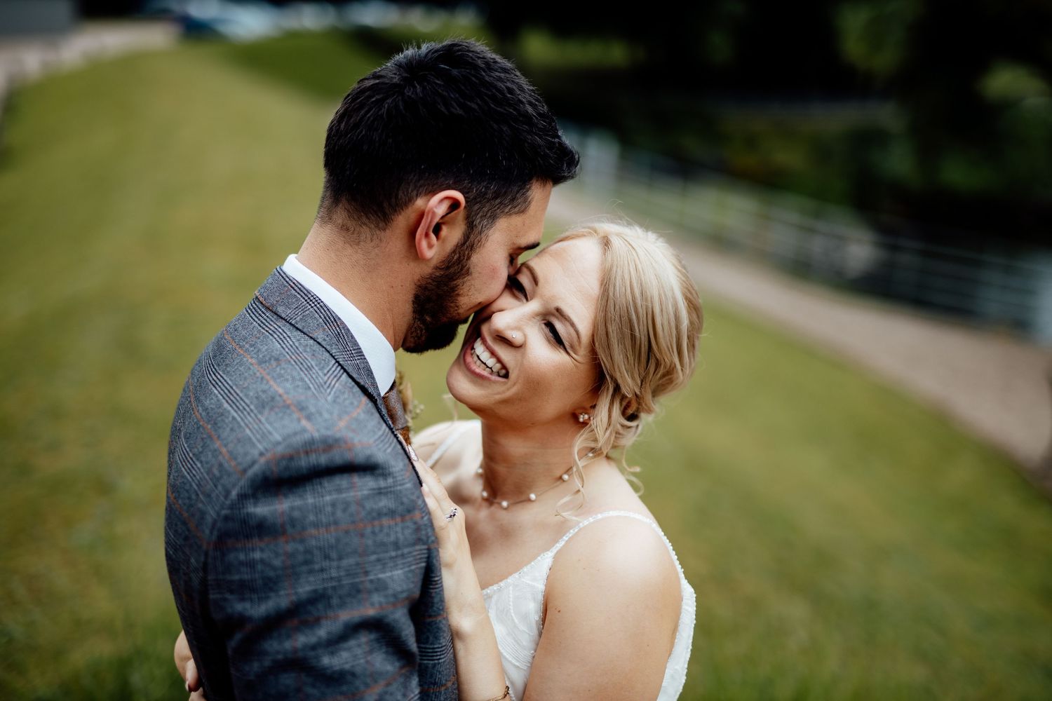 Romantic outdoor wedding portraits on green lawn near historic building.