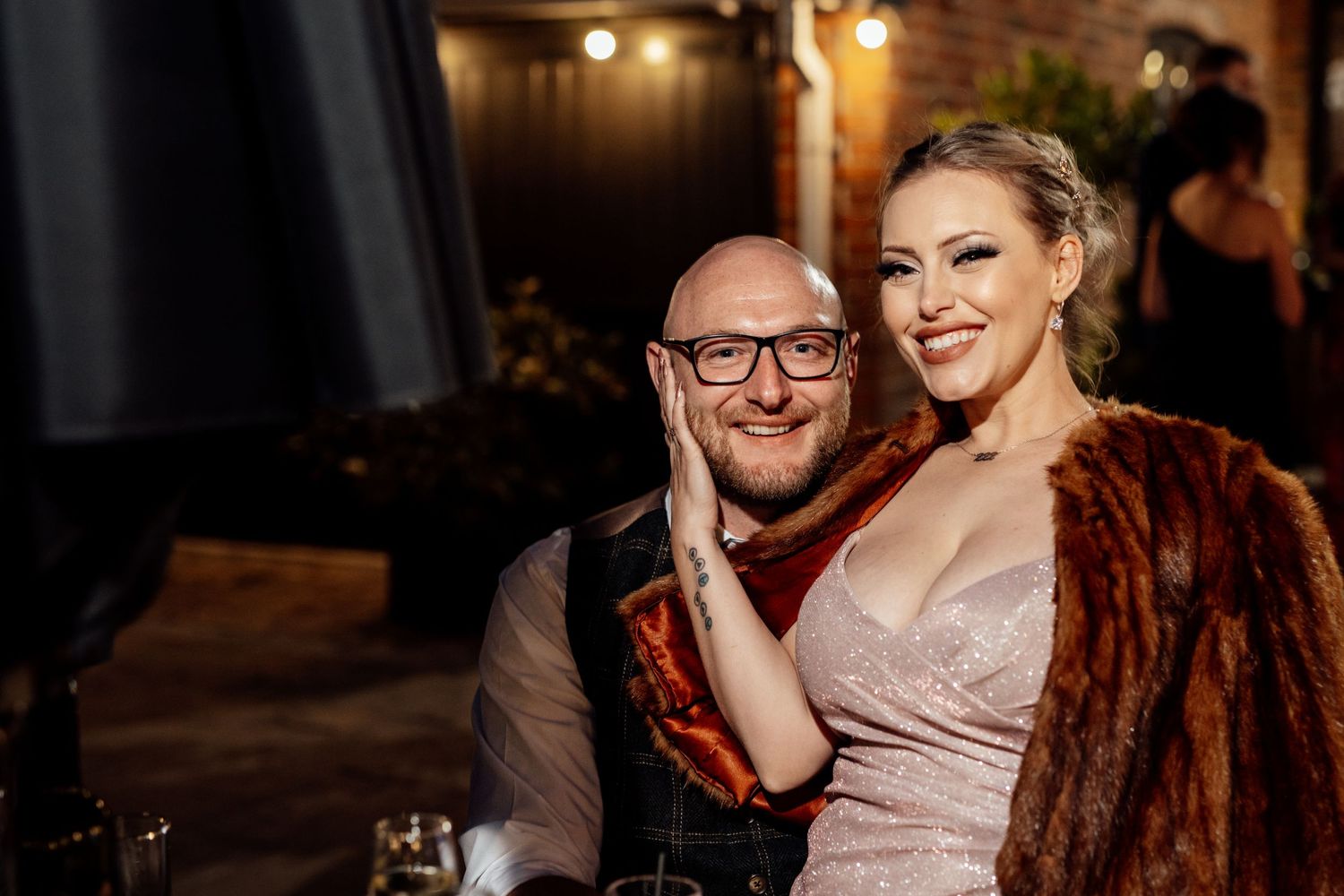 Wedding reception guests enjoying lively celebration in dimly lit venue.