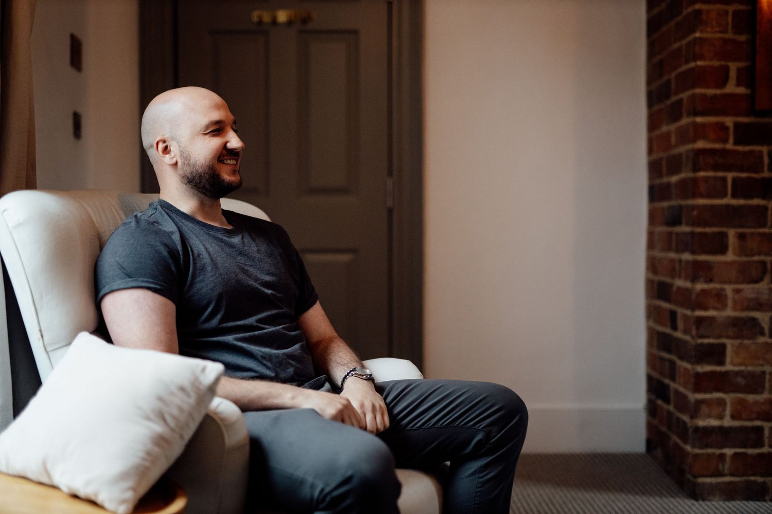 Intimate pre-wedding moments in room with exposed brick wall and natural lighting.
