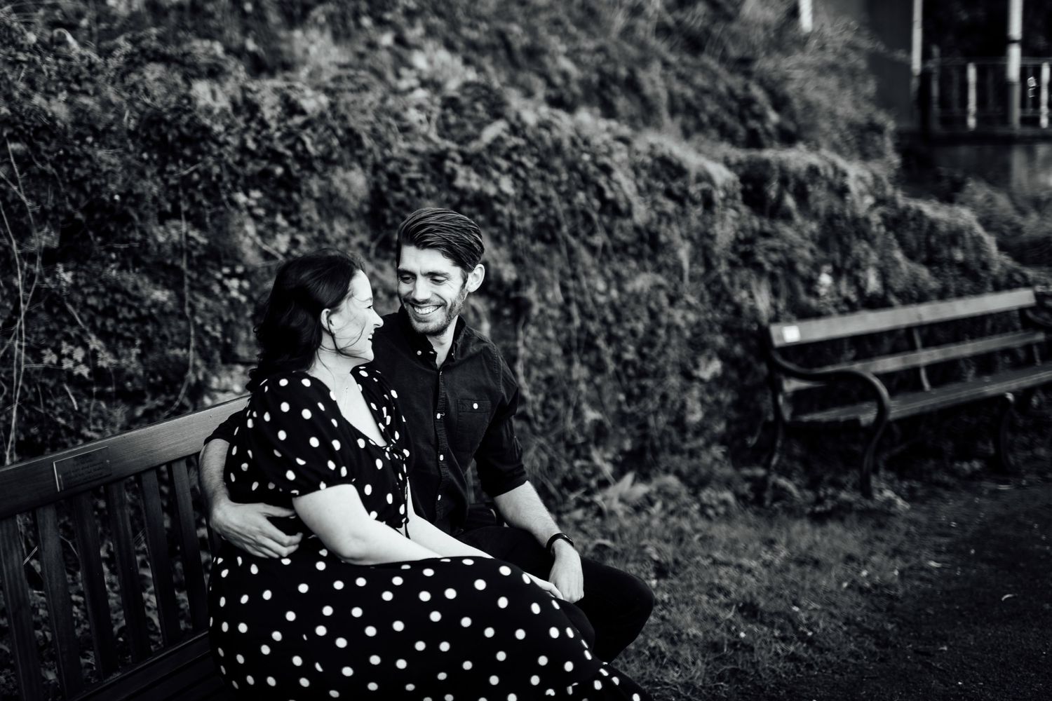 A romantic couple shares an intimate moment in a rainy outdoor setting with an umbrella.