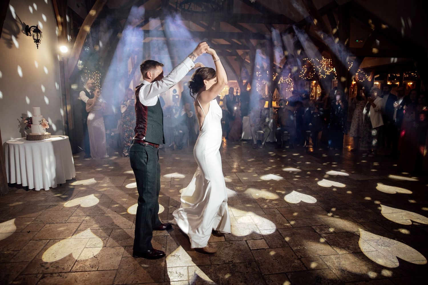 Couple dancing at wedding reception under sparkling lights and disco ball.