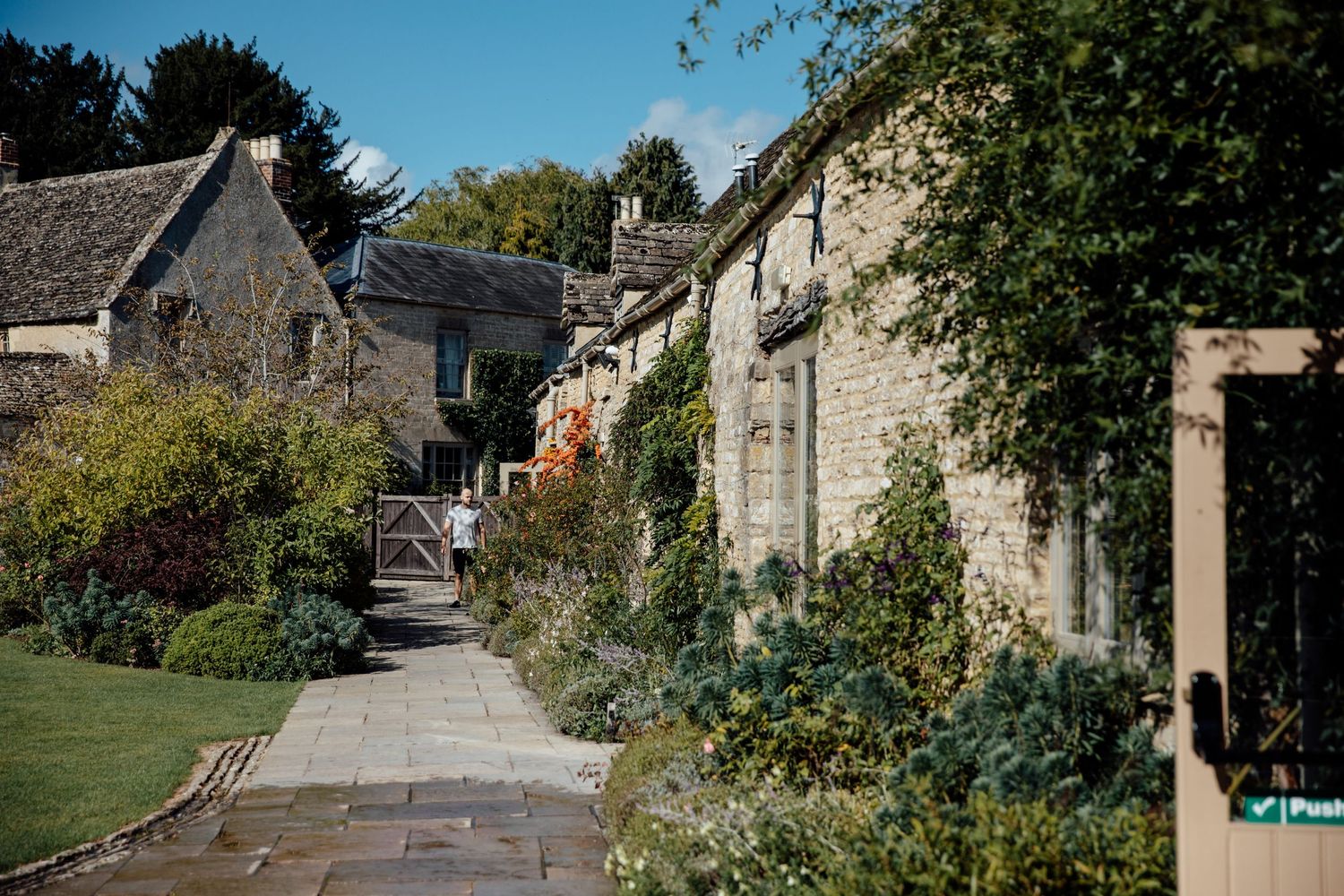 Charming countryside village street with stone cottages and garden landscaping.