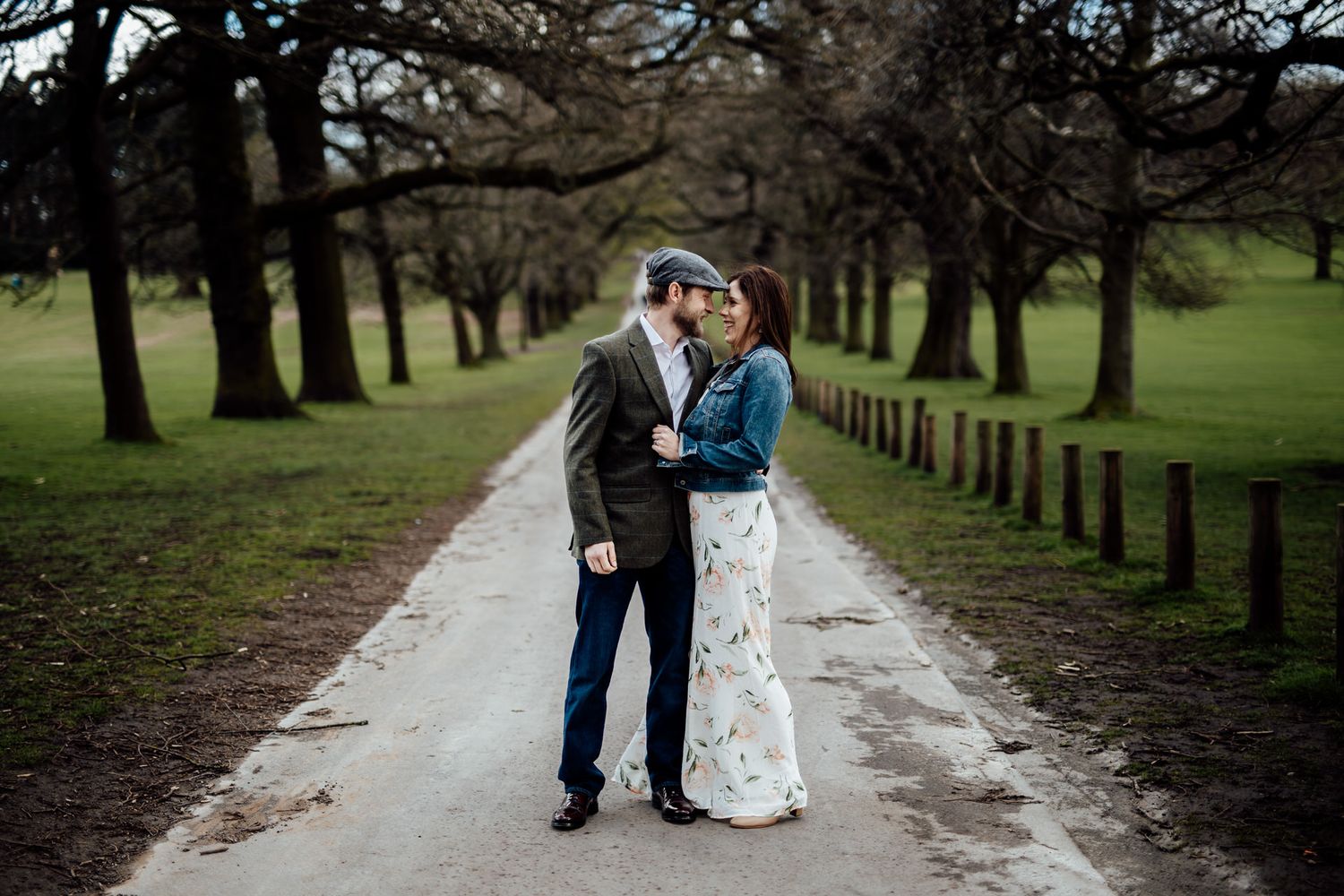 A couple walks together along a tree-lined path in a park setting.