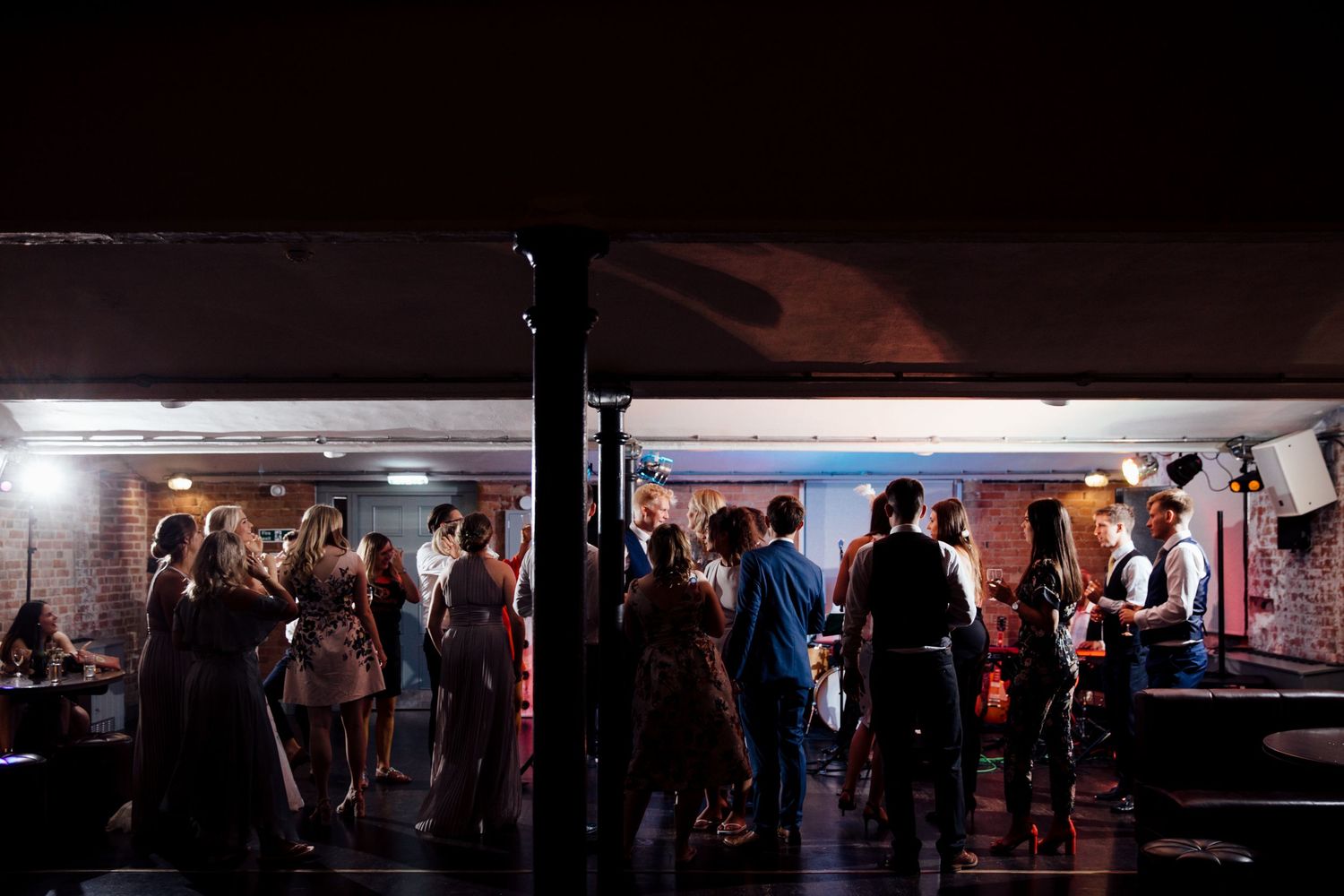 Silhouettes of wedding guests dancing in a dimly lit reception venue.