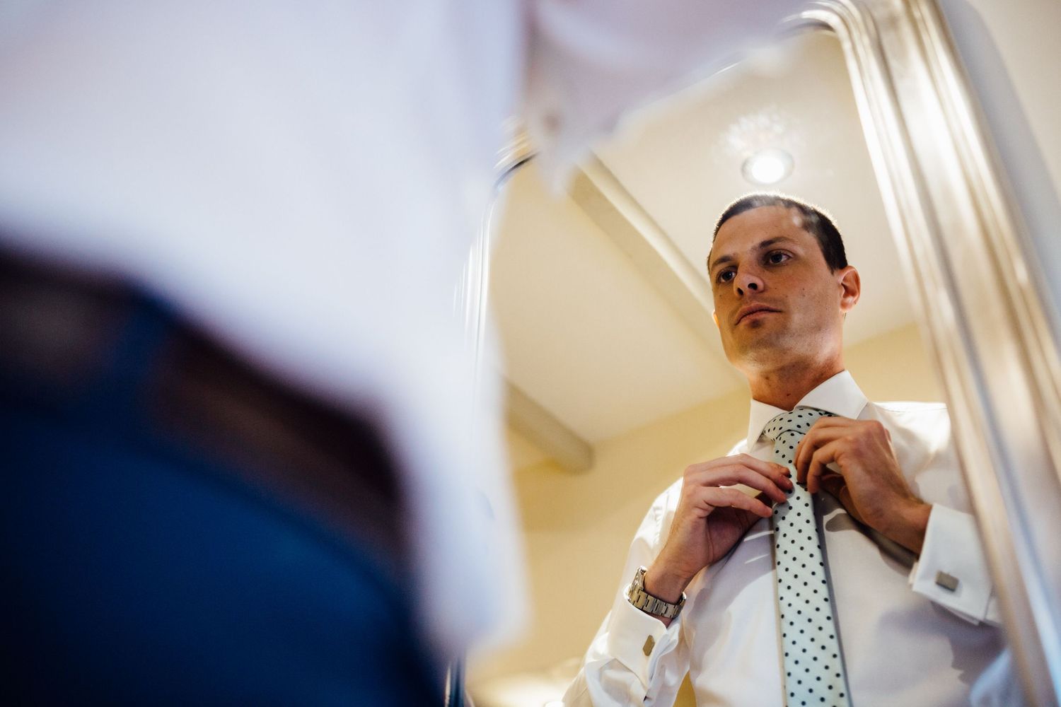 Men in formal wear preparing for an event in an elegant room with white decor.