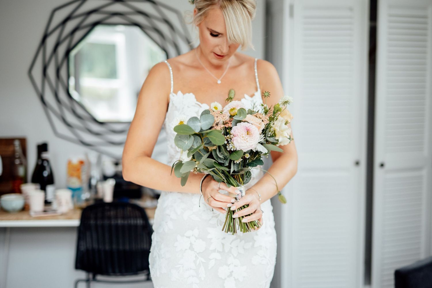 Elegant white wedding bouquet with roses and greenery against a light background.