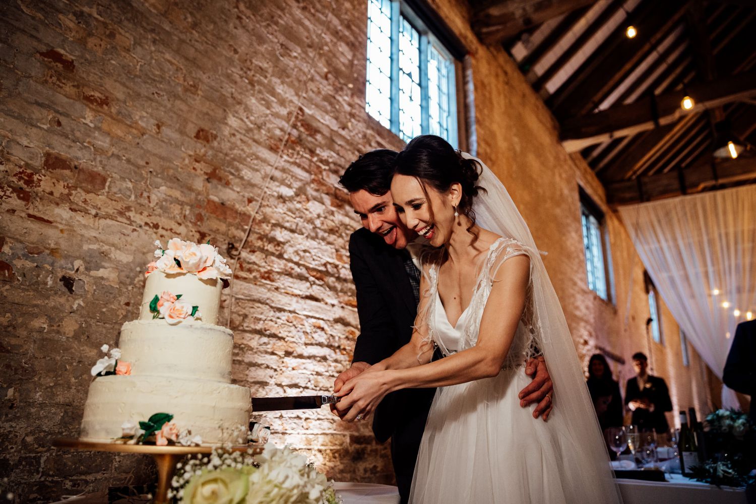Romantic wedding reception in a converted brick barn with string lights and high ceilings.