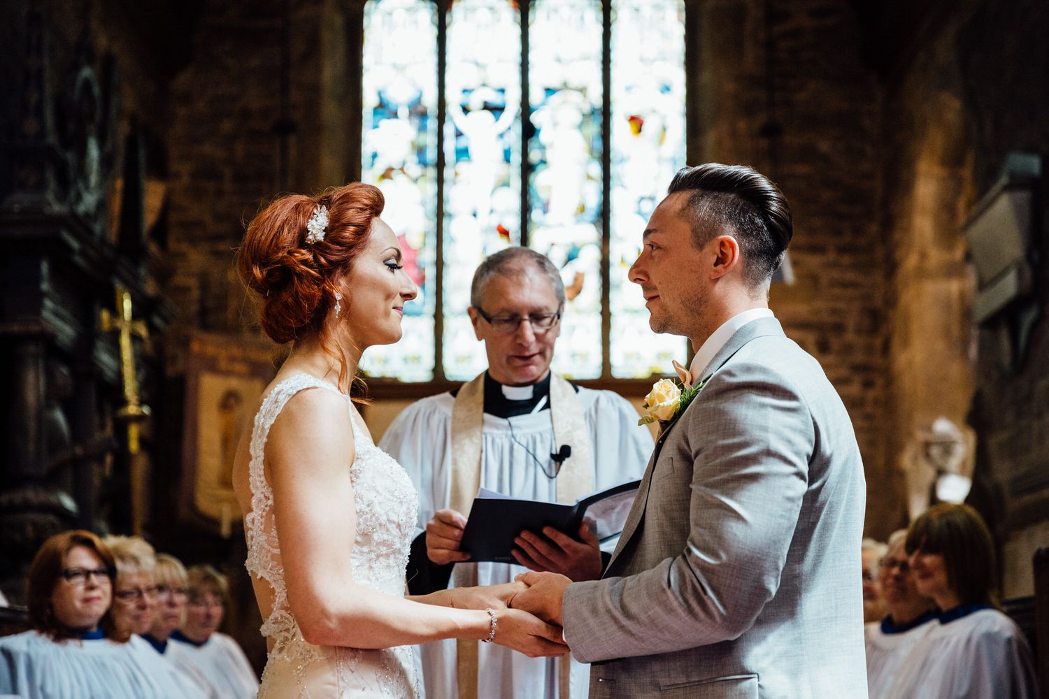 A romantic wedding ceremony takes place inside a beautiful historic stone church with stained glass windows.