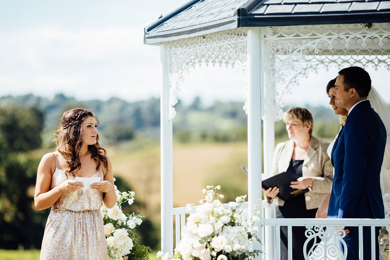 Couple shares romantic moments on a sunny porch with white columns and decorative trim.
