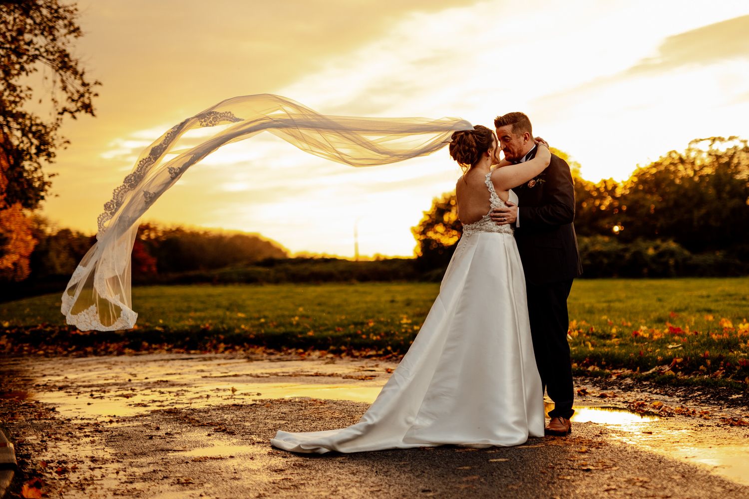 Romantic sunset wedding portrait with bride's veil flowing in the golden light.