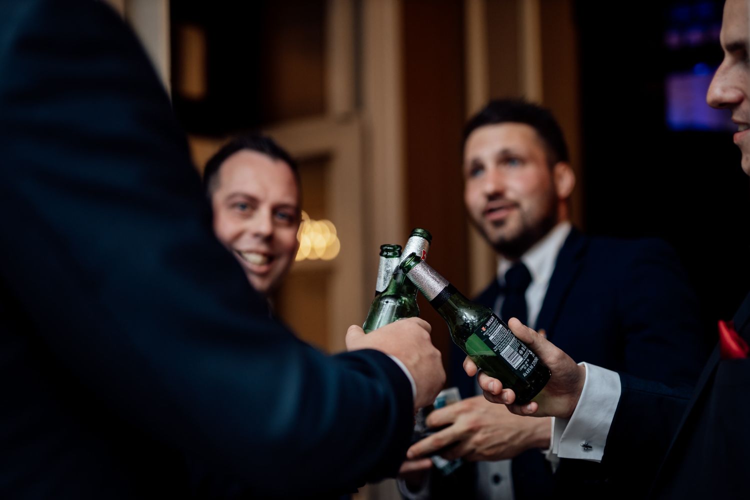 Wedding party members toast with champagne bottles in formal attire.