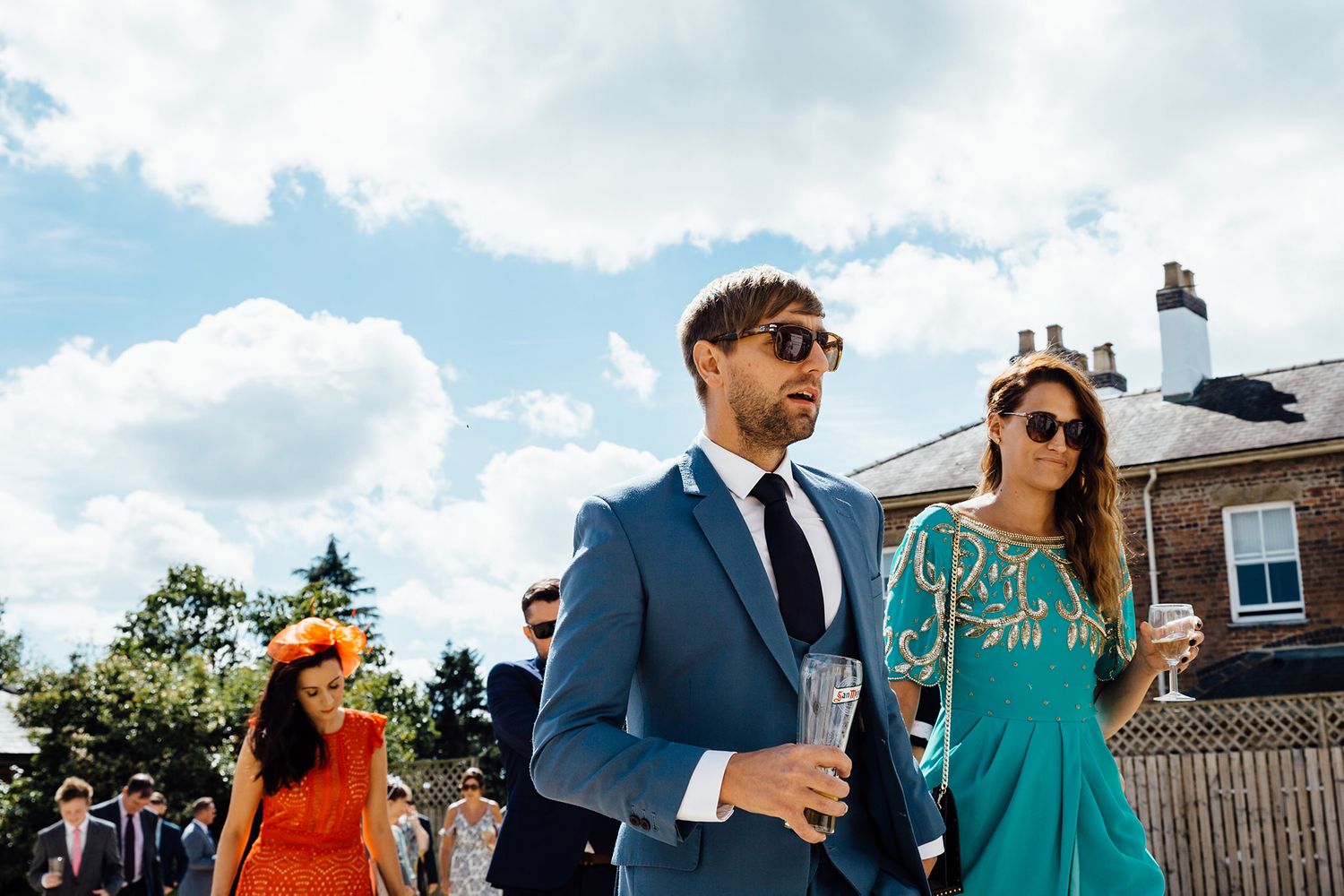 Wedding guests mingling outdoors on a cloudy summer day.