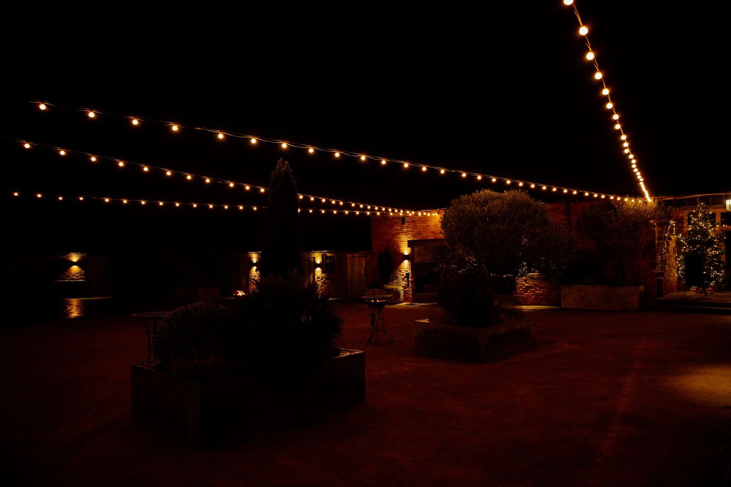 String lights create a romantic ambiance at an outdoor nighttime wedding venue.