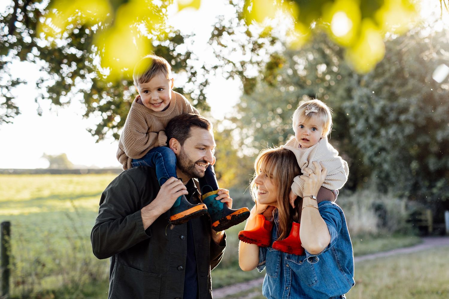 Playful outdoor family moment captured with sunlit yellow foliage in background.