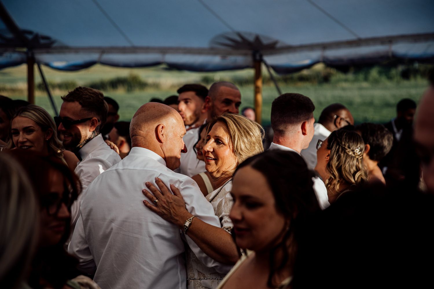 Wedding reception guests dancing and celebrating during evening festivities.