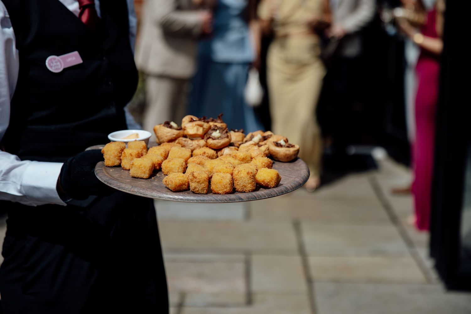 Elegant wedding reception with guests enjoying appetizers served on silver platters.