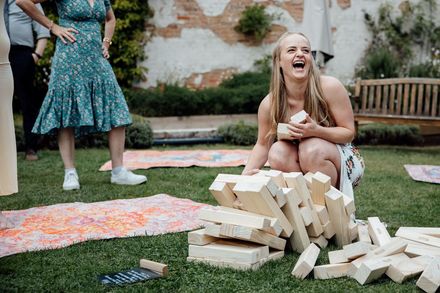 Guests laughing while playing with large wooden blocks during outdoor wedding festivities.