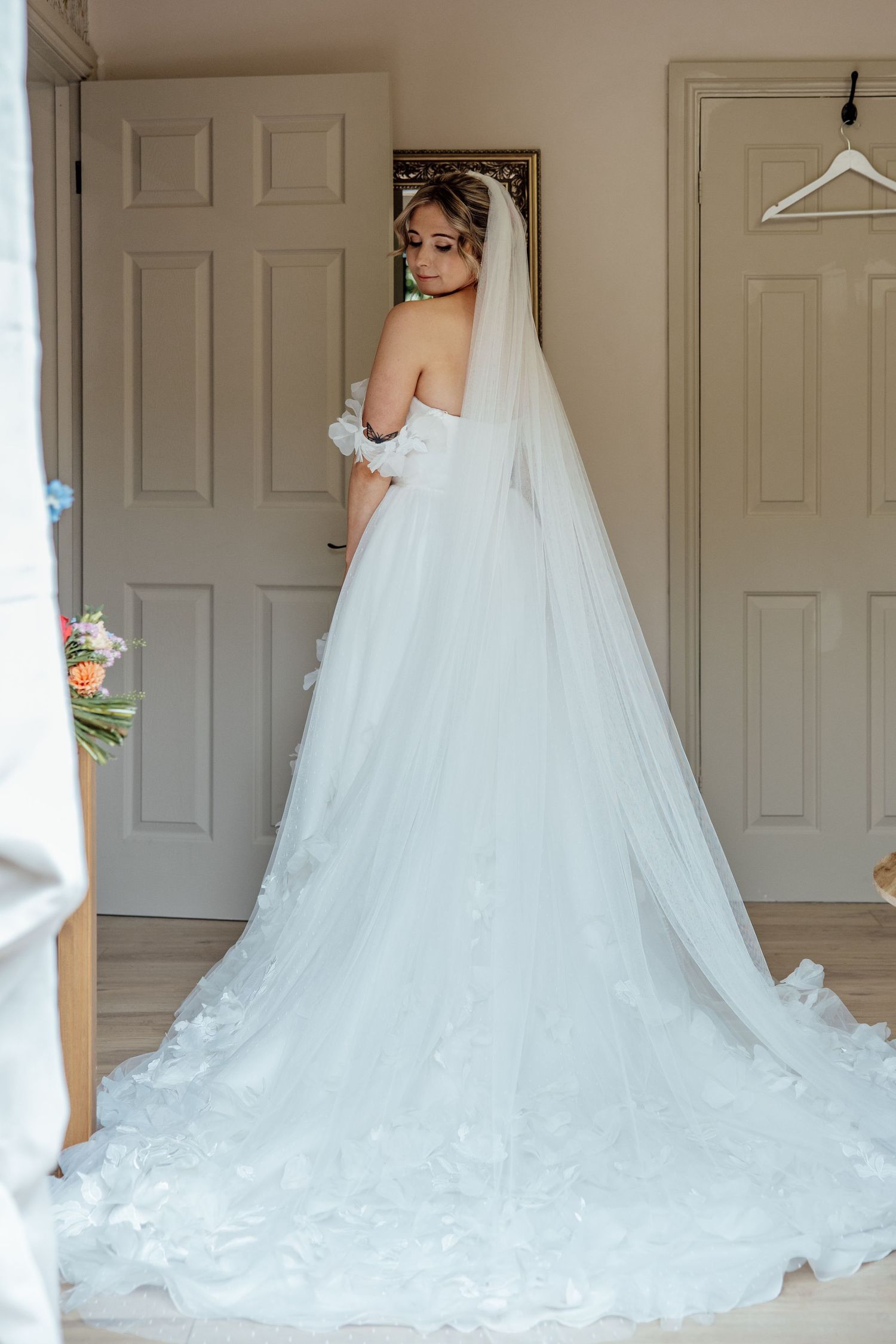 Long flowing white wedding dress with dramatic train displayed in a room.