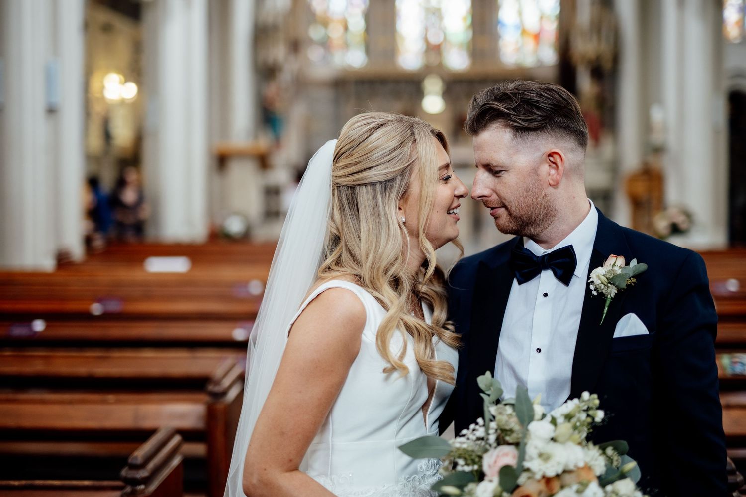 Intimate wedding ceremony moments inside historic church with stained glass windows.