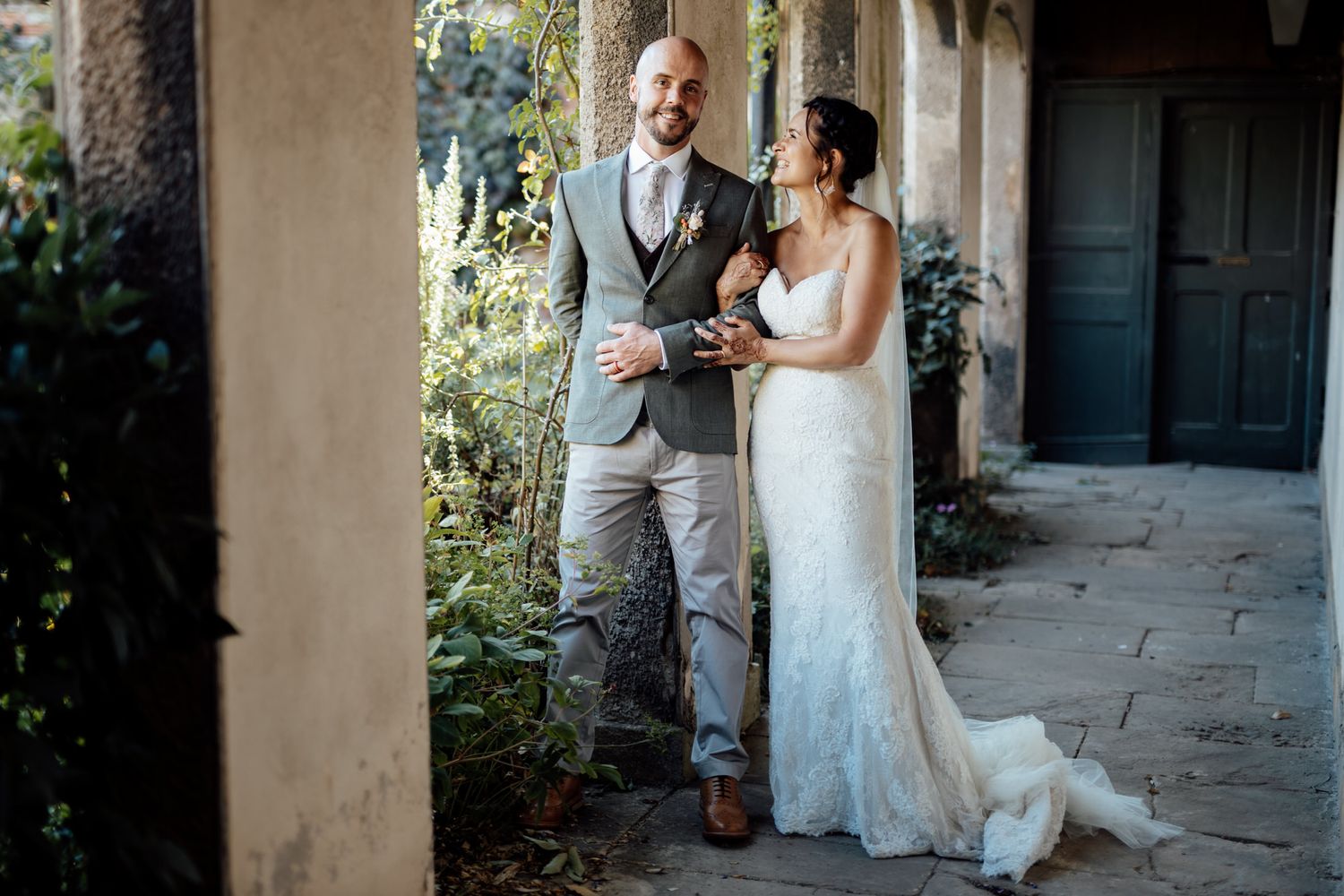 Couple shares intimate moments along a covered garden walkway.