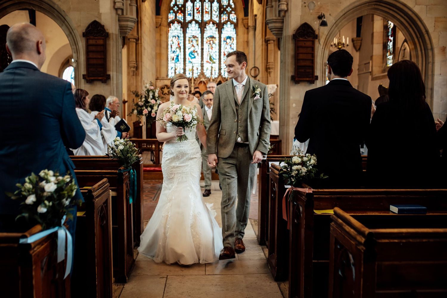Traditional church wedding ceremony in a gothic-style chapel with stained glass windows.