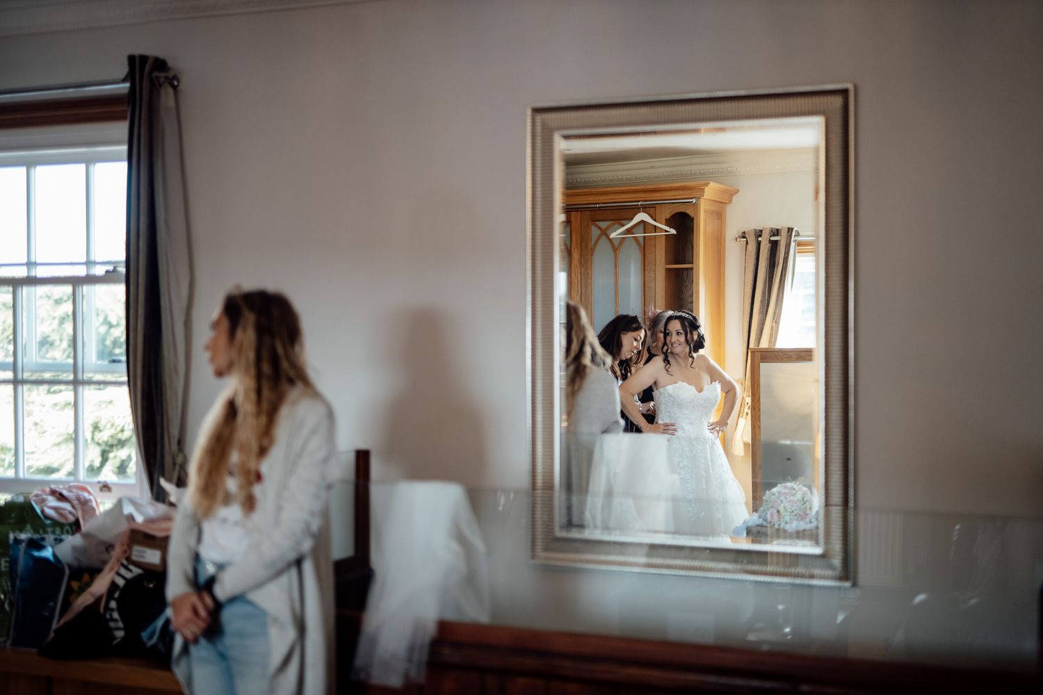 Elegant wedding preparation scene reflected in framed mirror against neutral wall.