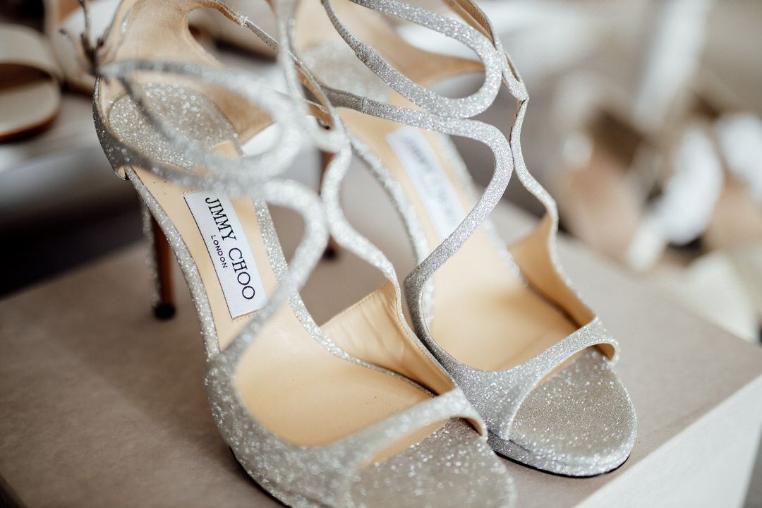 Sparkly silver Jimmy Choo bridal shoes with strappy details on display.