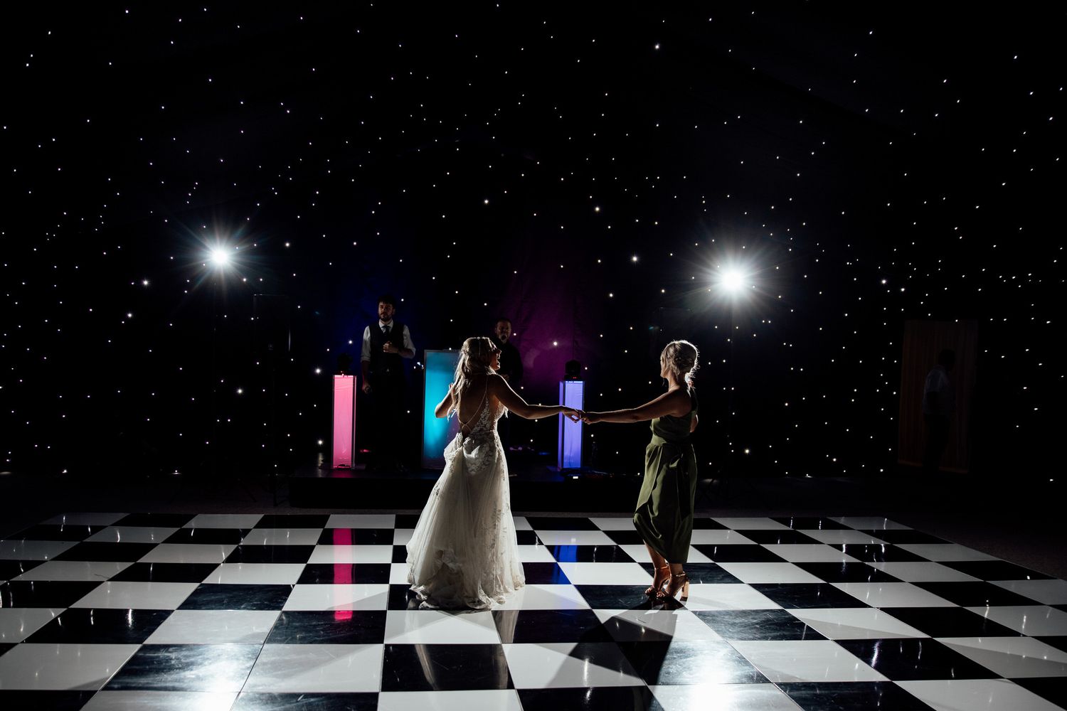 Dramatic wedding photoshoot on black and white checkered floor with starry night backdrop.