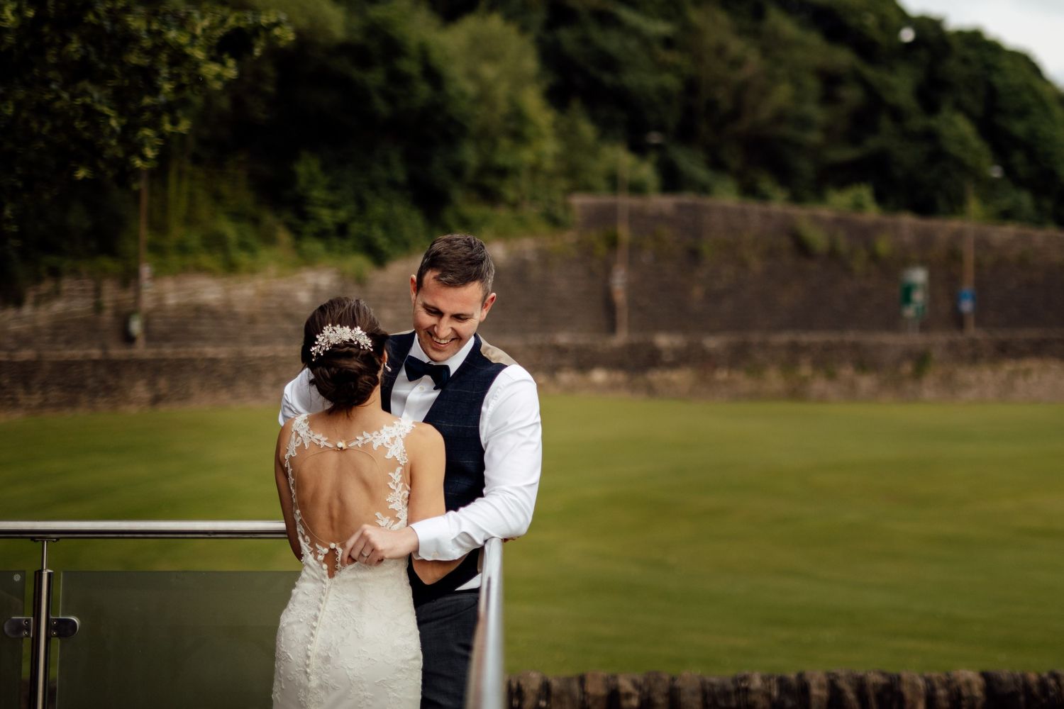 Newlyweds sharing a romantic moment in a sprawling green field.