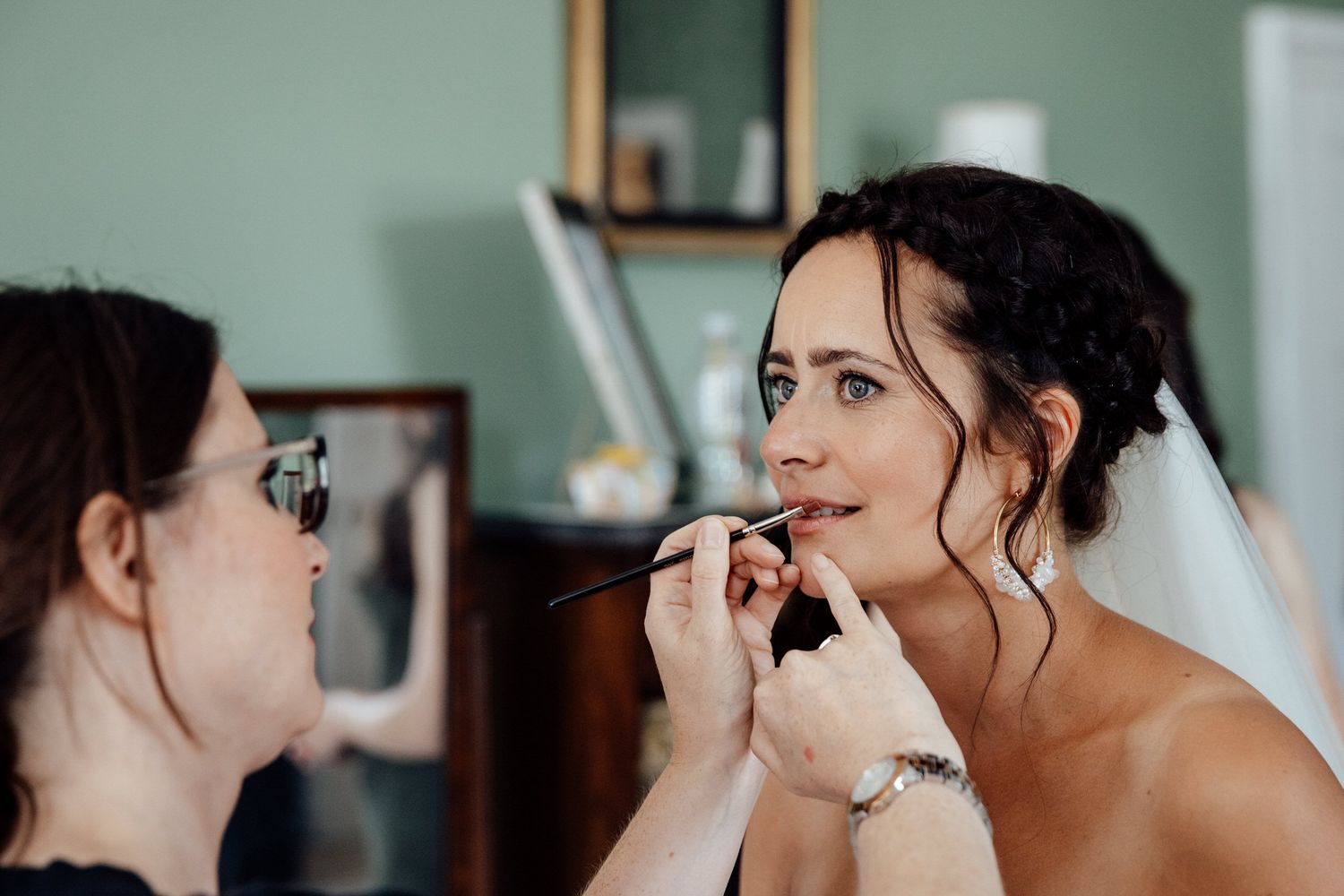 Close-up shots of bridal makeup application in natural window light.