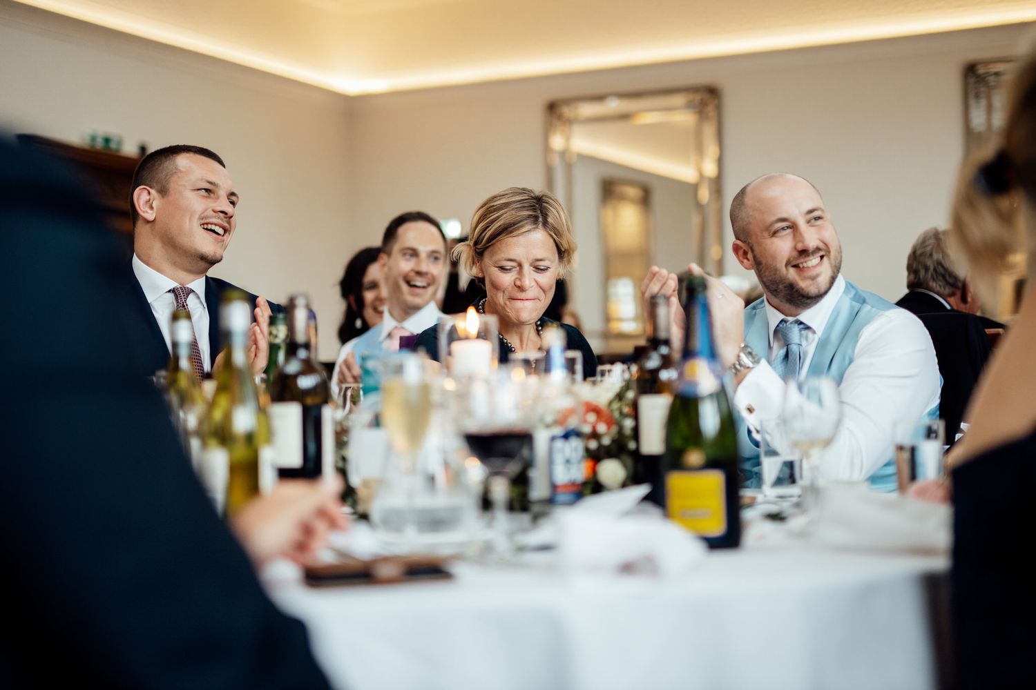 Wedding reception guests enjoying conversation and laughter at a banquet table.